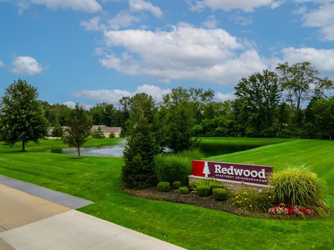A sign that says Redwood in front of a grassy area.