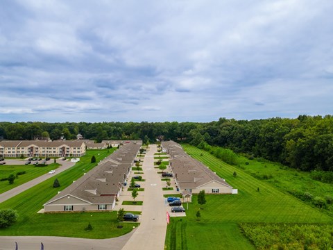 A row of houses with green lawns and trees in the background.