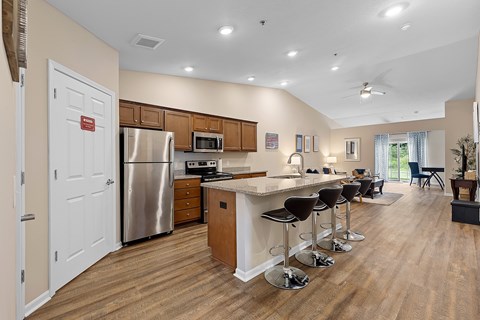 A kitchen with a refrigerator, stove, and bar stools.