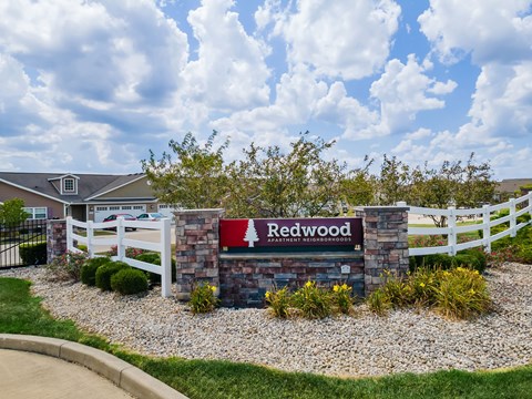 A sign that says Redwood in front of a white fence.