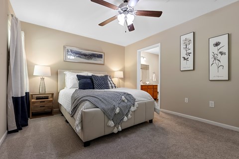 A bedroom with a bed, nightstand, and a ceiling fan.