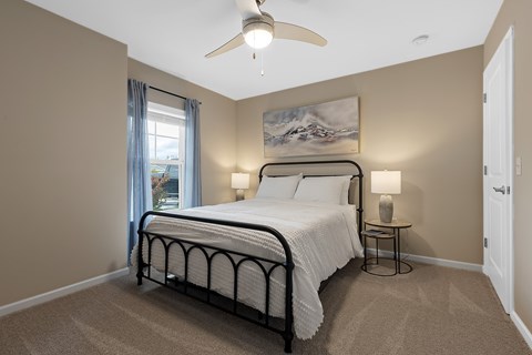 A bedroom with a large bed and a ceiling fan.