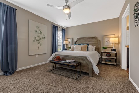 A bedroom with a bed, nightstands, and a ceiling fan.