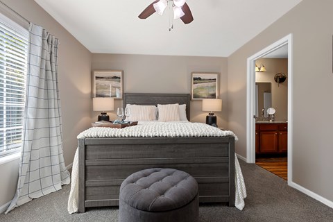 A bedroom with a bed, a ceiling fan, and a window with curtains.