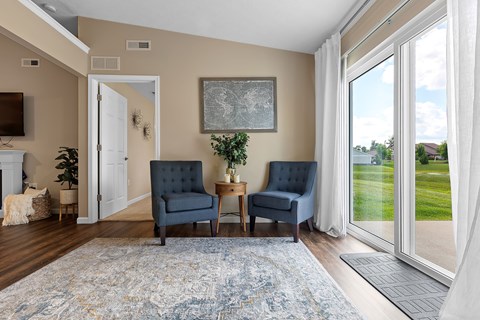 A living room with a blue rug and two chairs.
