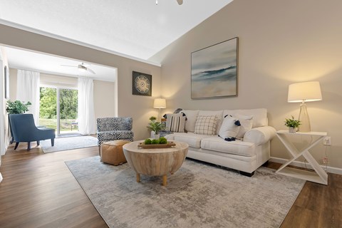A living room with a white couch, a wooden coffee table, and a painting on the wall.