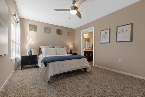 A bedroom with a bed, nightstand, and a ceiling fan.