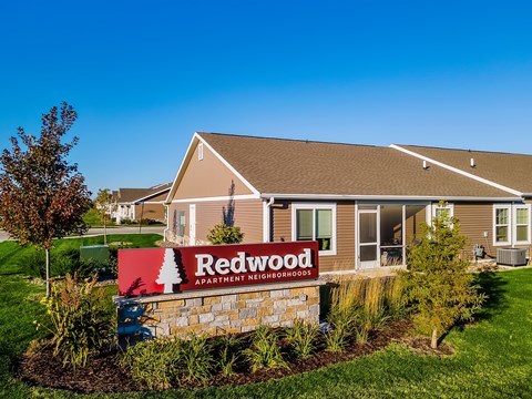 A sign for Redwood Apartment Homes is in front of a building.