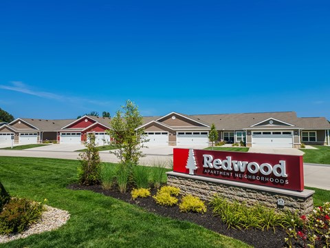 A sign for Redwood Apartment Neighborhoods stands in front of a building.