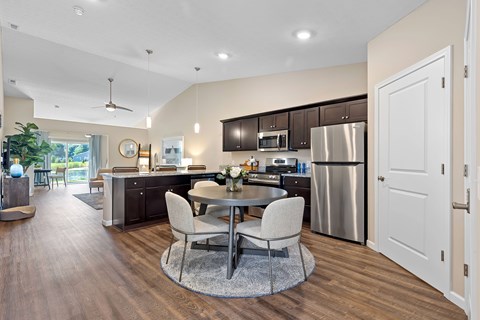 A modern kitchen with a dining table and chairs in the middle of the room.