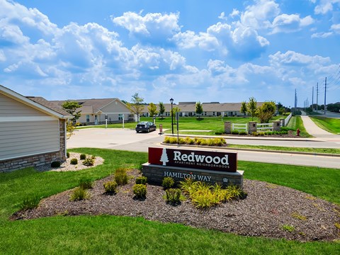 A sign for Redwood Estates is in the foreground of a grassy area.