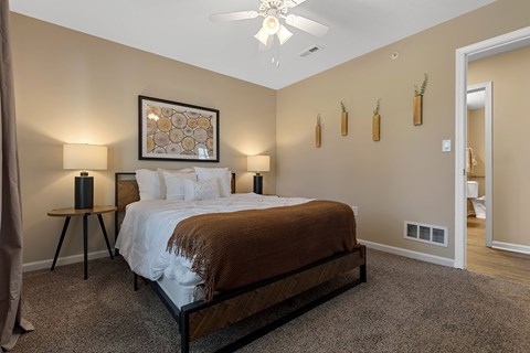 A bedroom with a large bed and a ceiling fan.