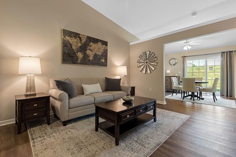 A living room with a beige couch, a coffee table, and a large painting on the wall.