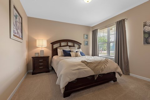 A bedroom with a large bed and a window with curtains.
