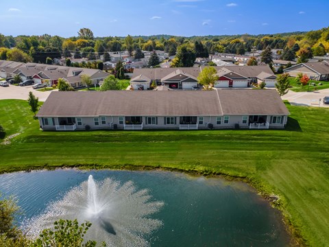 A fountain in the middle of a pond in front of a building.