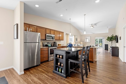 A kitchen with a refrigerator, microwave, oven, and a dining table with chairs.