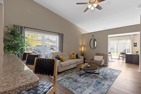 A living room with a couch, chairs, and a ceiling fan.