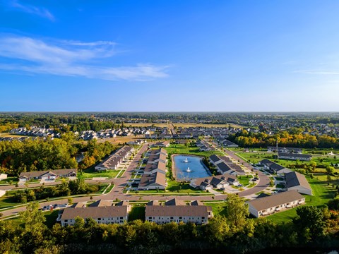 A bird's eye view of a residential area with houses, a swimming pool, and a green lawn.