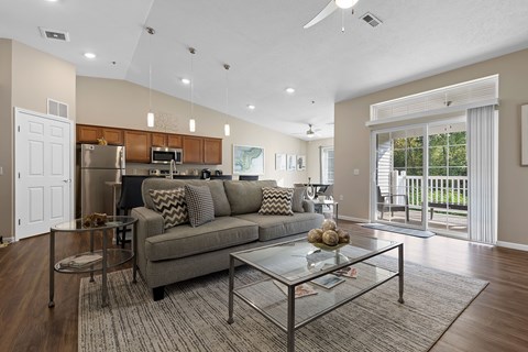 A modern living room with a grey couch and a glass coffee table.