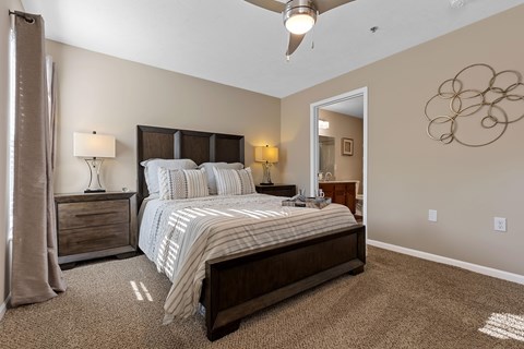 A bedroom with a large bed and a ceiling fan.