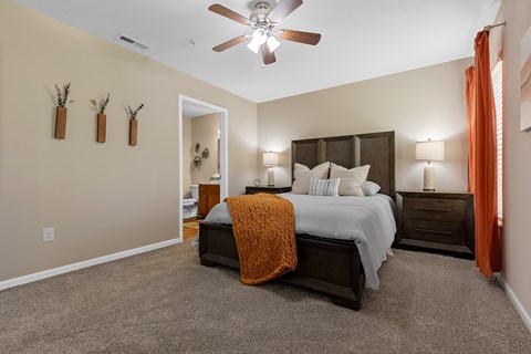 A bedroom with a bed, nightstands, and a ceiling fan.