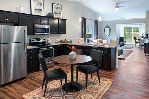a kitchen and dining room with black cabinets and stainless steel appliances