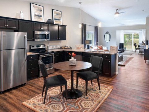 a kitchen with black cabinets and stainless steel appliances and a table