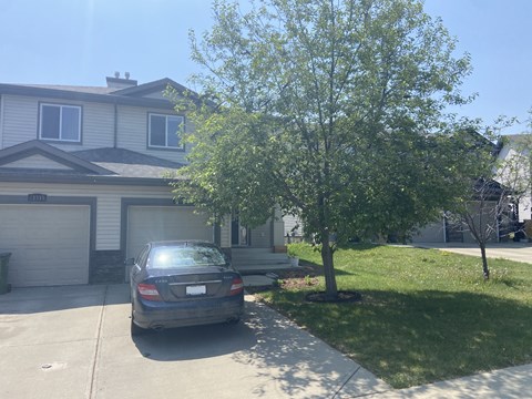 A car is parked in a driveway in front of a house.