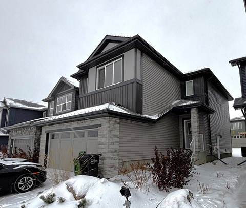 A house with a grey exterior and a black car parked in front.