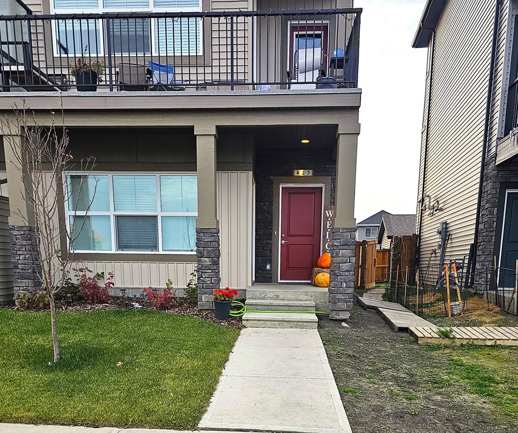 A house with a red door and a balcony with a table and chairs.