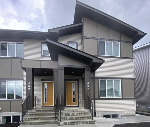 A modern house with a grey exterior and a brown front door.