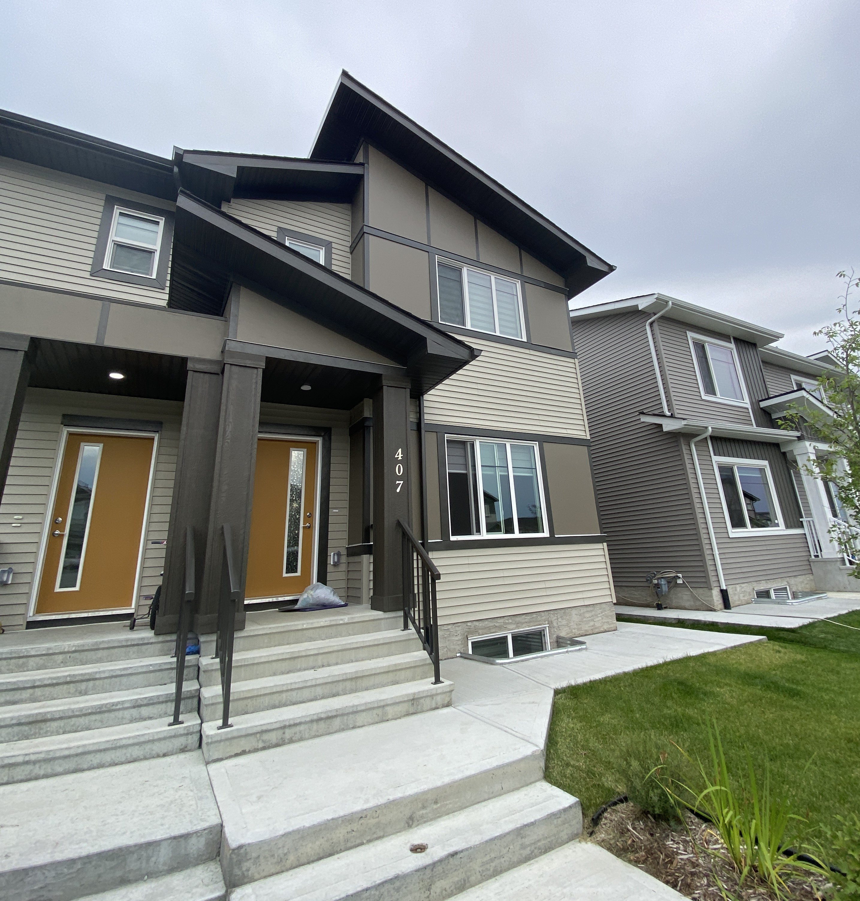 A modern house with a brown door and a grey facade.