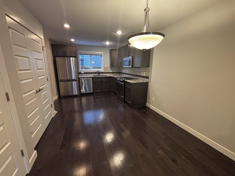 A kitchen with dark wood floors and white walls.