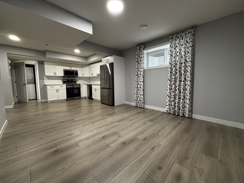 A kitchen with wooden floors and a window with curtains.
