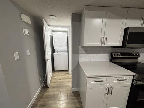A kitchen with white cabinets and a white refrigerator.
