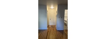 A hallway with a white door and wooden floors.