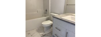 A white toilet sits in a bathroom next to a bathtub and sink.