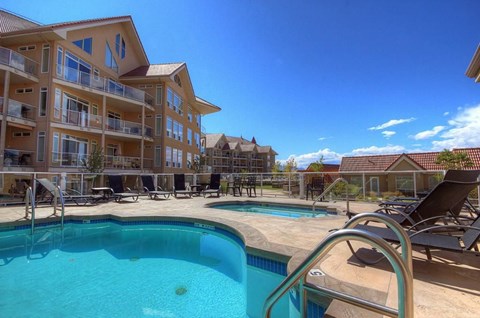 A large swimming pool in front of a resort style building.