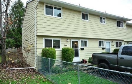 A house with a tan siding and a grey truck parked in front.