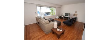 A living room with a couch, chair, and television.