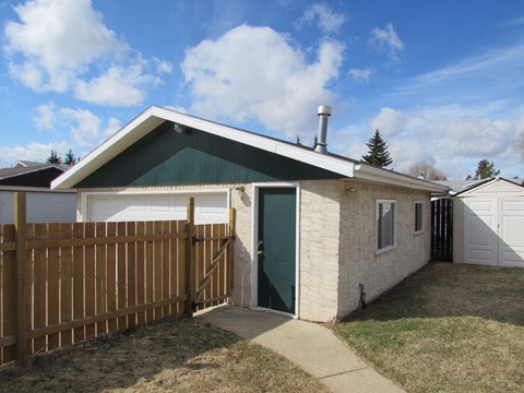 A small house with a green door and a brown fence.
