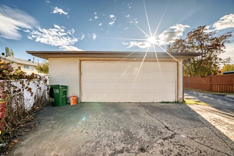 A garage with a white door is under a bright sun.