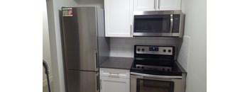 A kitchen with a stainless steel refrigerator, microwave, and stove.