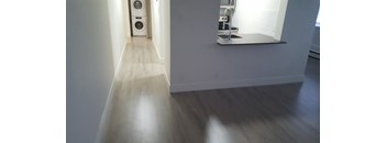 A long hallway with a washing machine at the end.