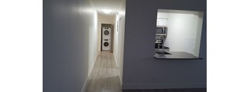 A hallway with a washing machine on the left and a kitchen on the right.