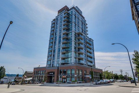 A tall building with many windows is in the middle of a street.