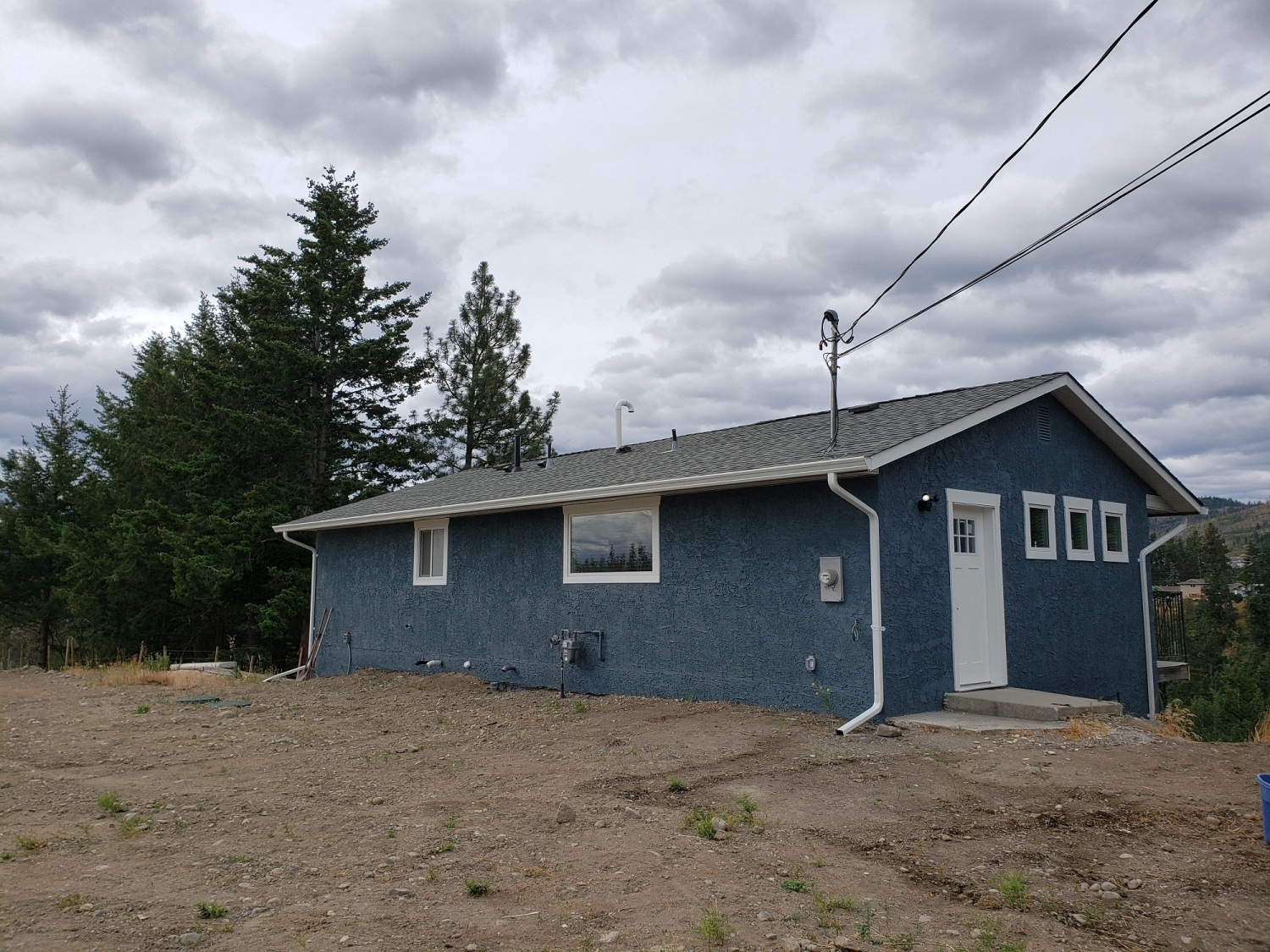 A blue house with a white door and windows sits in a field.