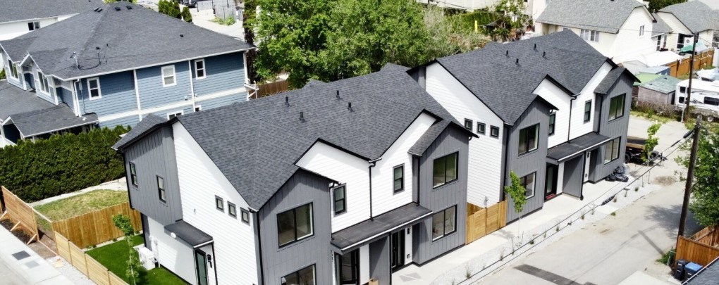 A row of houses with grey roofs and white walls.