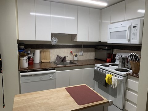 A kitchen with a white oven and a white microwave.