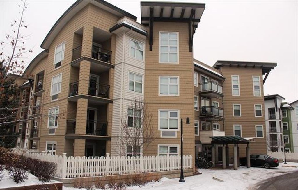 A large apartment building with a white picket fence in front.